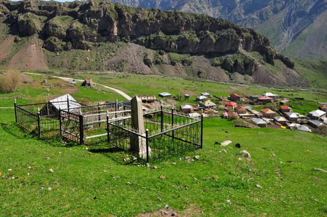 Umzäunte Gräber am Hang, unten das Dorf Gergeti Friedhof Georgien bei Gergeti
